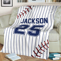 Baseball throw blanket draped over a chair, featuring pinstripes, stitched baseball details, and bold lettering