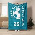Teal soccer throw blanket displayed with large white soccer ball artwork in a living room