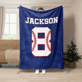 Navy baseball throw blanket displayed in a living room with a bold white sports graphic