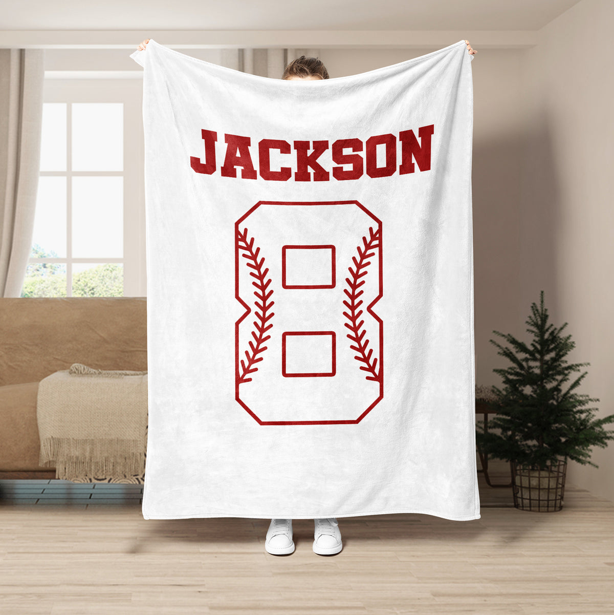 White baseball throw blanket displayed in a living room with contrasting red baseball stitching artwork