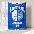 Blue basketball throw blanket held up indoors with a large basketball graphic and athletic typography