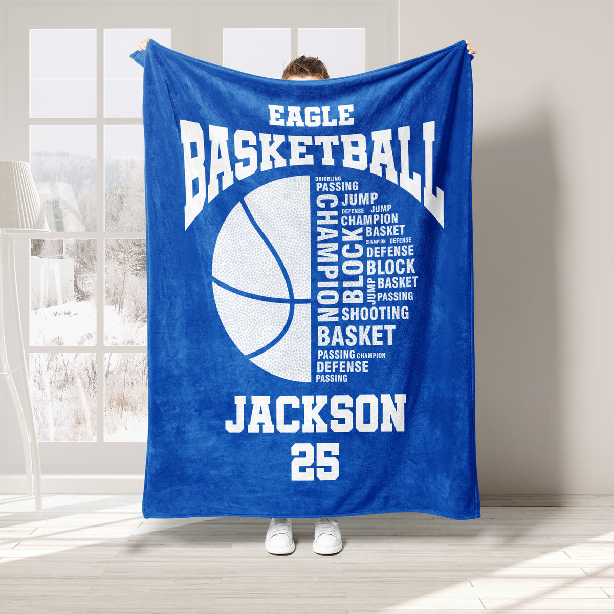 Blue basketball throw blanket held up indoors with a large basketball graphic and athletic typography