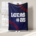 Baseball throw blanket displayed with white player silhouettes, red stitching details, and navy sports artwork