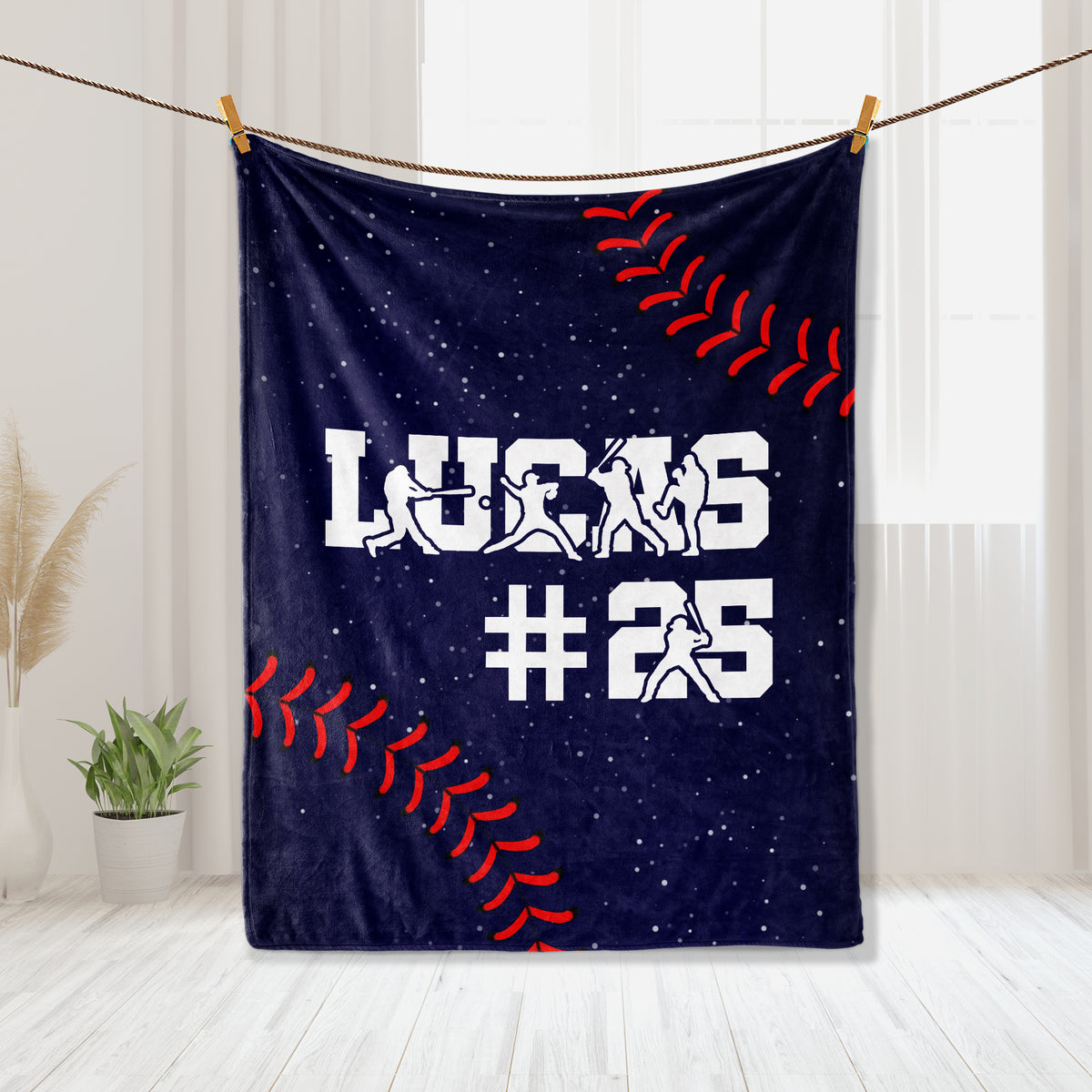 Baseball blanket hanging in a bright room with player silhouettes, baseball stitching, and navy artwork