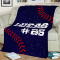 Baseball throw blanket draped over a couch with player silhouettes, red stitching, and navy background