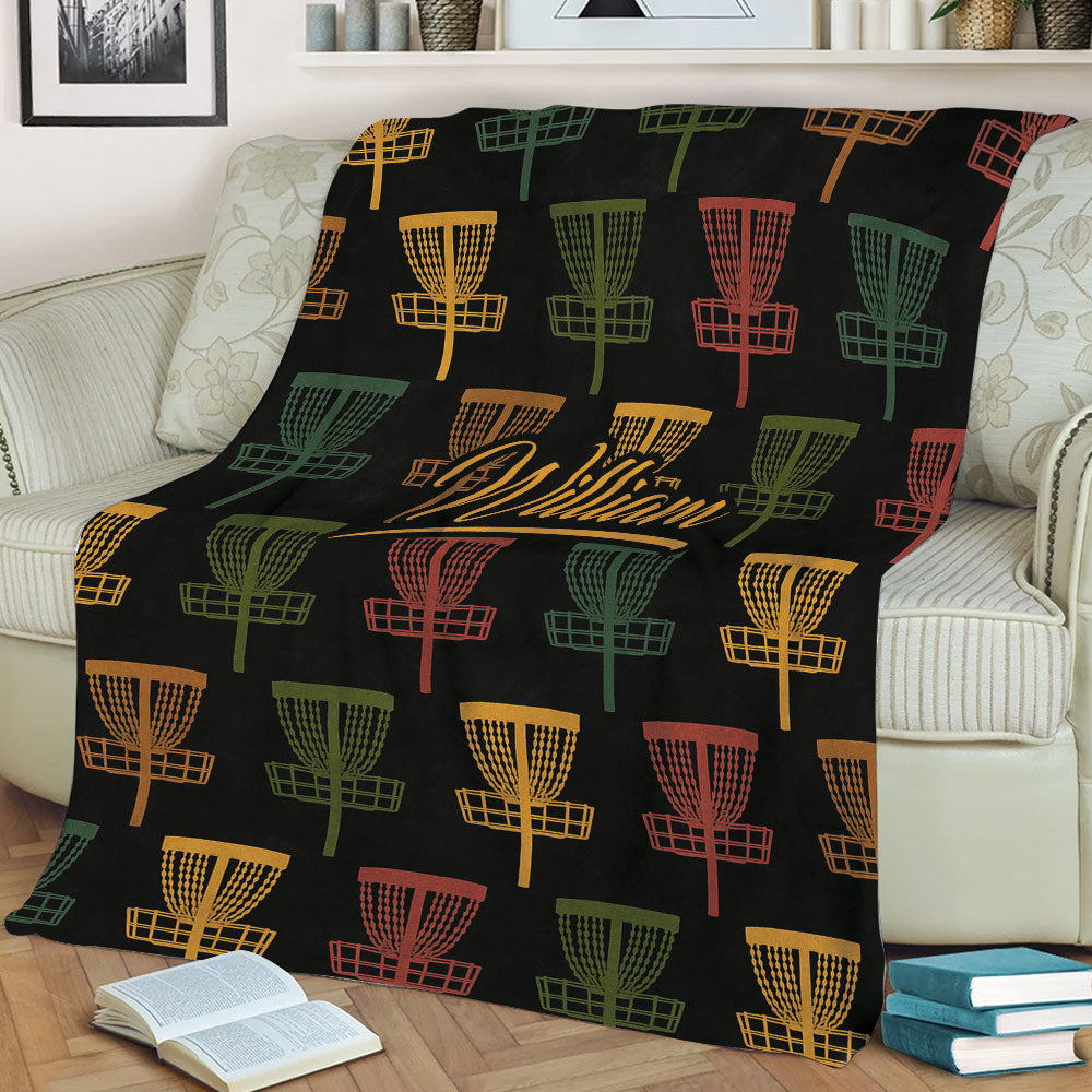Disc golf throw blanket displayed on a sofa with multicolor basket graphics