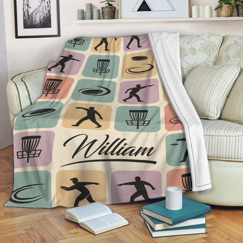 Disc Golf throw blanket draped over a sofa, featuring pastel sports artwork and disc golf imagery