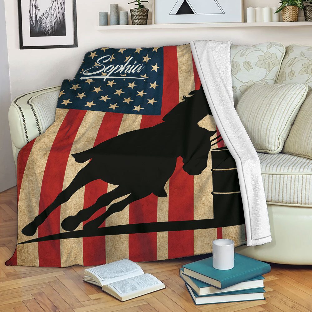 Patriotic barrel racing throw blanket draped over a sofa with a horse and cowgirl racing around a barrel