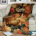 Close view of a sleeping fox blanket with detailed flowers and botanical artwork draped over a sofa