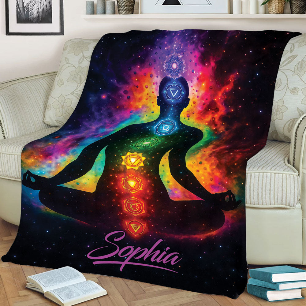 Cosmic chakra yoga blanket displayed on a sofa with a seated meditation figure