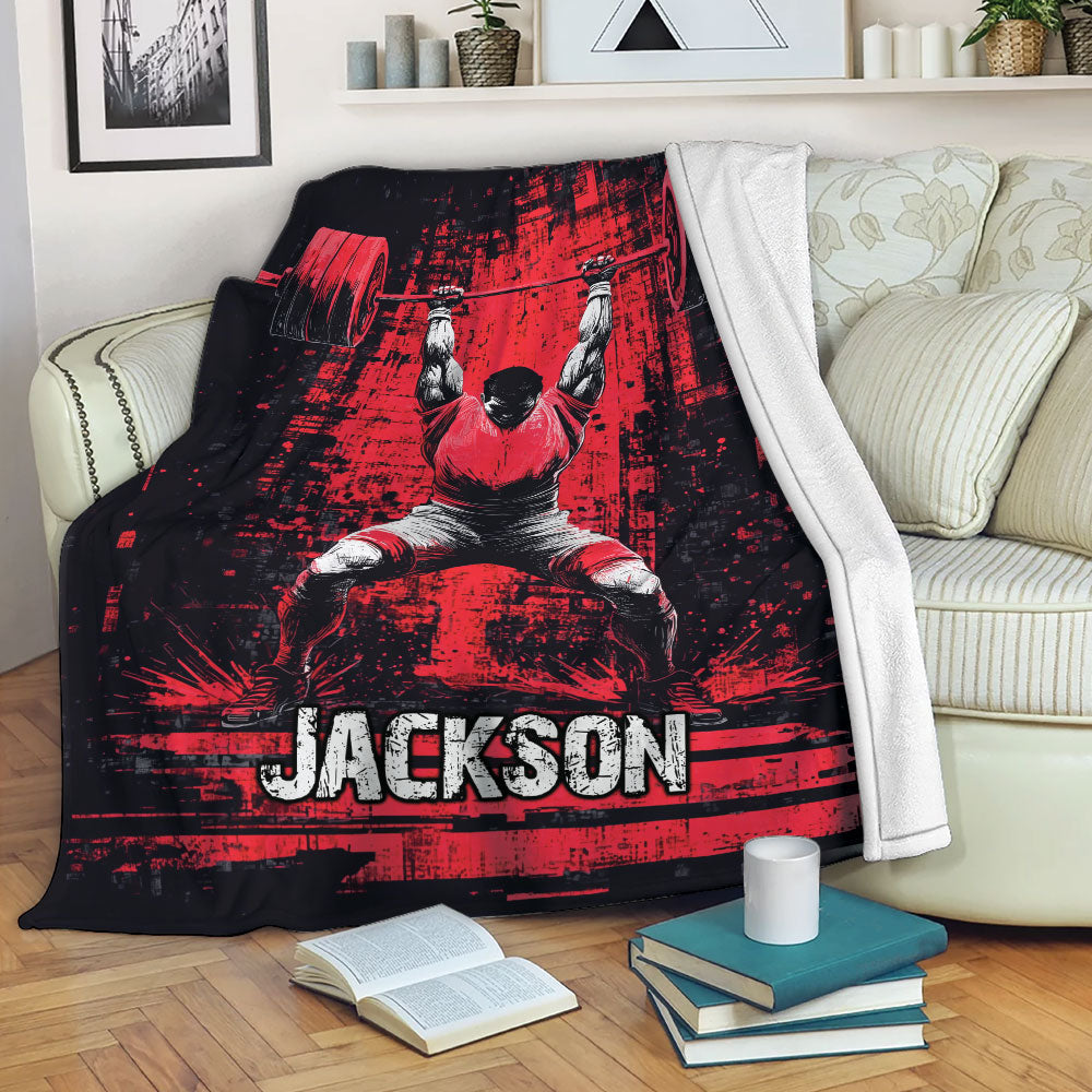 Red and black weightlifting blanket displayed on a sofa with barbell artwork