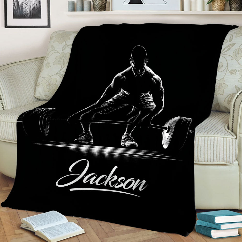 Close view of a black throw blanket with dramatic white weightlifting and barbell artwork