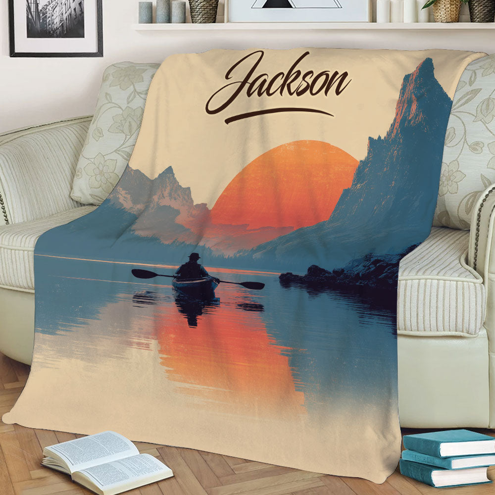Mountain lake kayak blanket displayed on a sofa with a warm sunset landscape