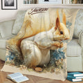 Close view of squirrel throw blanket featuring detailed floral woodland artwork on a sofa