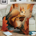Close lifestyle view of a squirrel blanket with fall foliage and acorn artwork on a couch