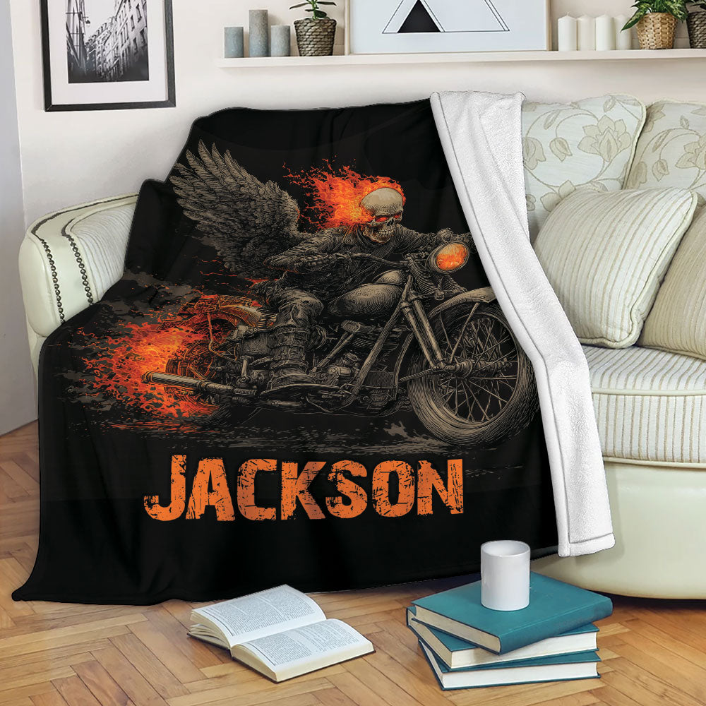 Biker throw blanket displayed on a sofa with fiery motorcycle skull artwork in black and orange