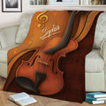 Close view of a violin throw blanket displayed on a sofa with rich brown musical artwork
