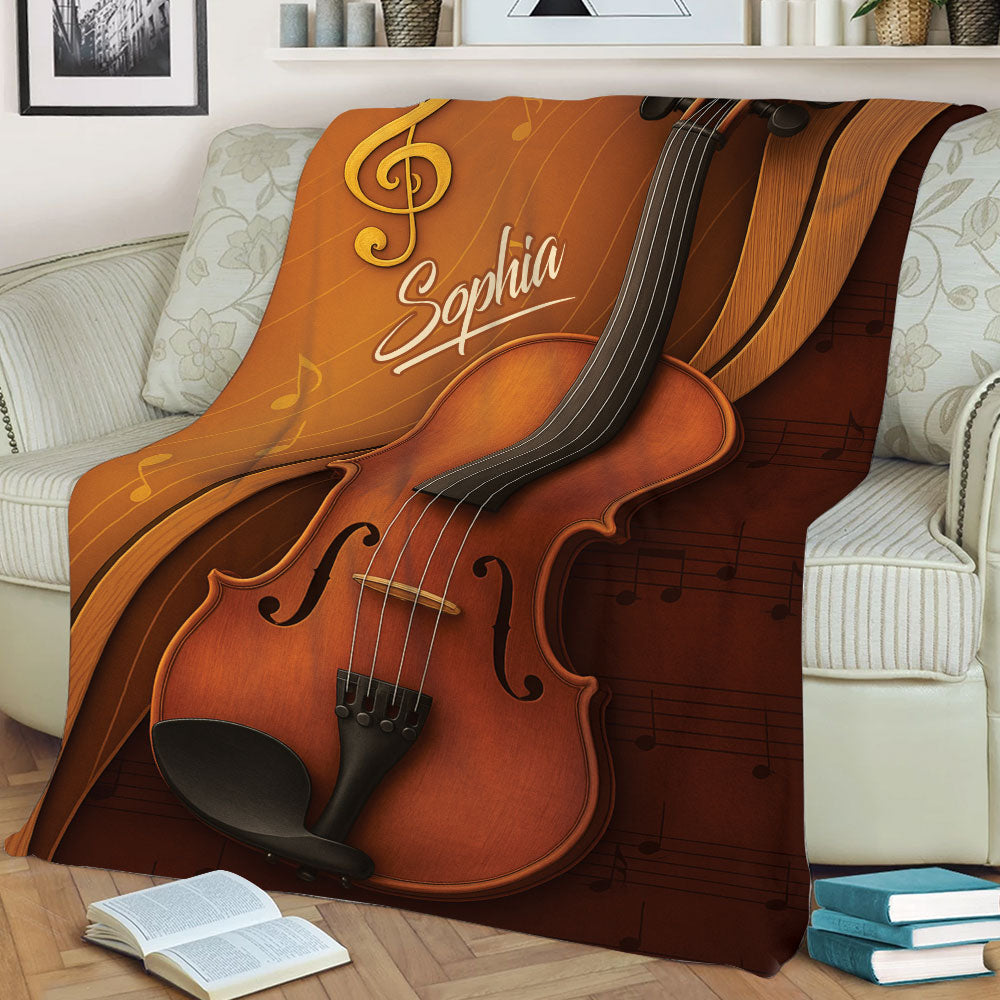 Close view of a violin throw blanket displayed on a sofa with rich brown musical artwork