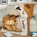 Close-up of cowgirl blanket showing ornate Western boots, cowboy hats, horseshoe, flowers, and rustic styling