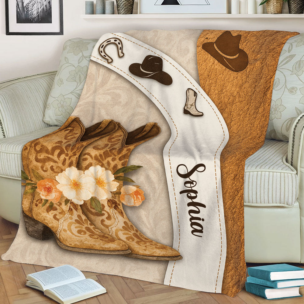 Close-up of cowgirl blanket showing ornate Western boots, cowboy hats, horseshoe, flowers, and rustic styling