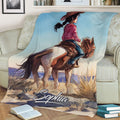 Western cowgirl riding artwork shown across a blanket draped over a sofa