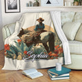 Cowgirl and horse blanket displayed on a sofa with desert cacti, colorful flowers, and rustic Western styling