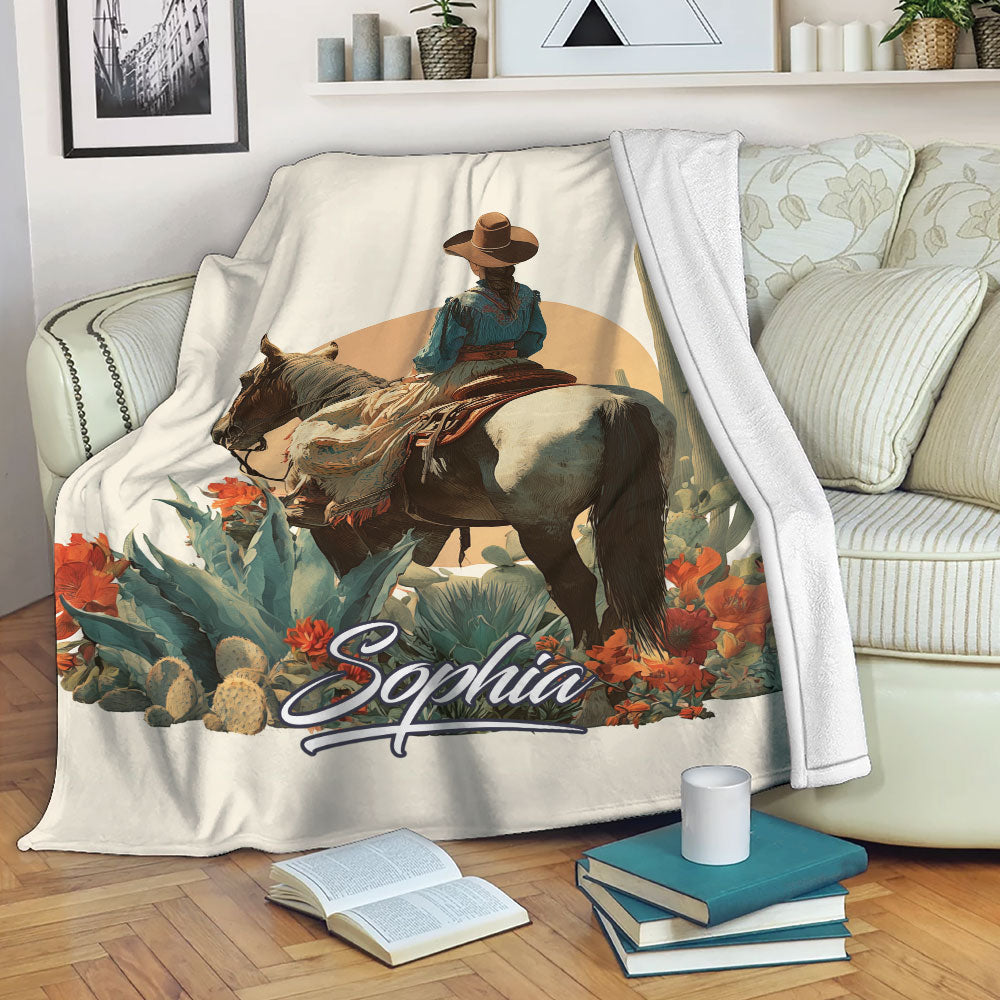 Cowgirl and horse blanket displayed on a sofa with desert cacti, colorful flowers, and rustic Western styling