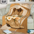 Rustic cowgirl throw blanket displayed on a sofa with ornate boots and cream flowers
