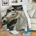 Horse throw blanket displayed on a sofa with elegant white horse artwork, lilies, and dark botanical details