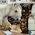 Close view of a white horse and botanical artwork on a decorative throw blanket