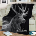 Close lifestyle view of a black throw blanket with detailed antlered deer artwork