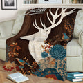 Close view of a decorative deer blanket featuring a white stag, birds, flowers, and dark woodland tones