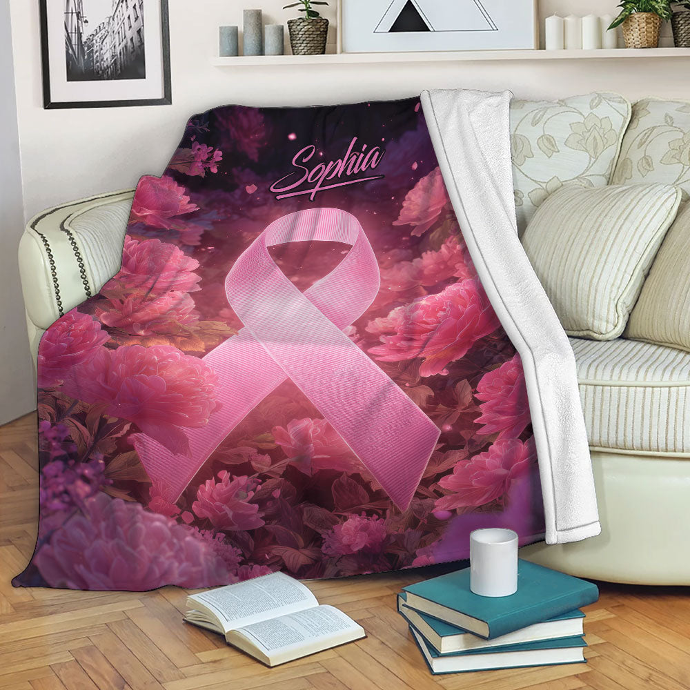 Breast cancer awareness throw blanket draped over a sofa with pink ribbon and floral artwork