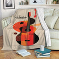 Guitar blanket draped over a sofa, featuring colorful acoustic guitar artwork in a cozy living room
