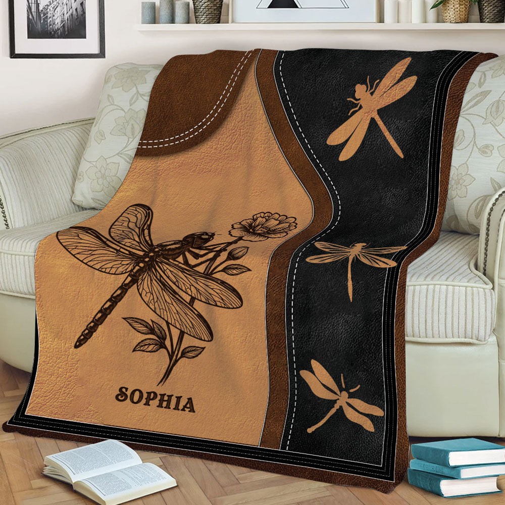 Close view of a dragonfly blanket draped over a sofa with botanical vintage-style artwork