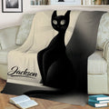 Close view of a black cat blanket displayed on a sofa with geometric neutral artwork