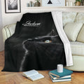 Black cat blanket draped over a sofa in a cozy living room with books and a coffee mug
