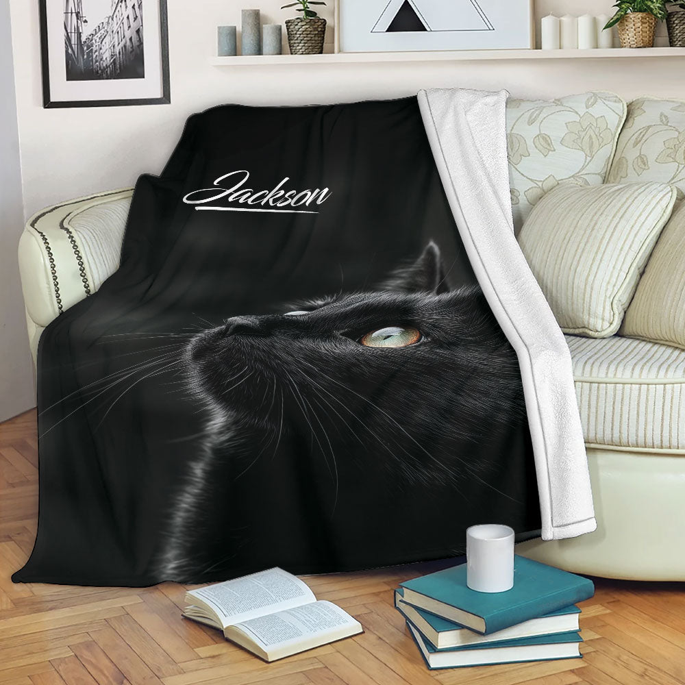 Black cat blanket draped over a sofa in a cozy living room with books and a coffee mug