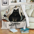 Black cat blanket draped over a sofa with moon phases, leaves, and neutral celestial artwork