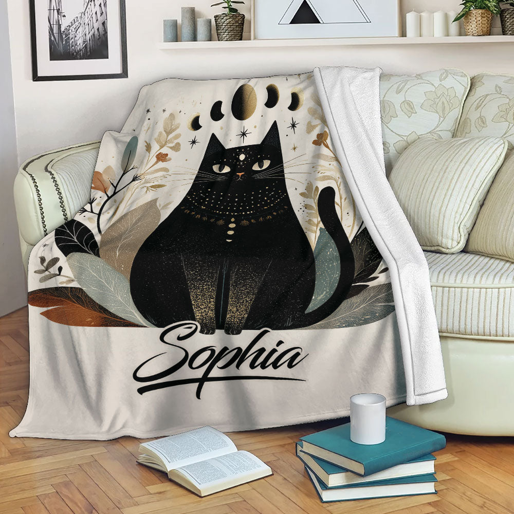 Black cat blanket draped over a sofa with moon phases, leaves, and neutral celestial artwork