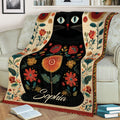 Decorative black cat blanket displayed across a sofa with vibrant flowers and botanical details