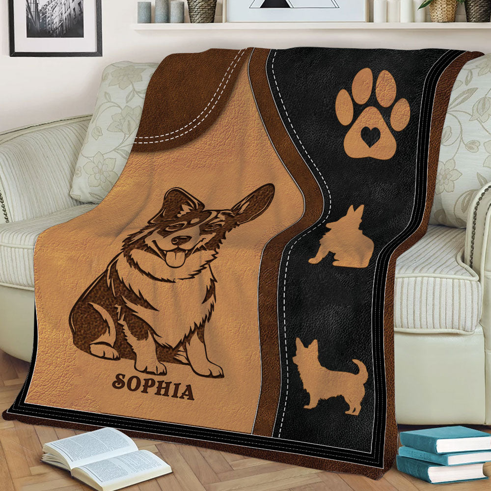 Close view of Corgi blanket artwork with paw motif, dog silhouettes, and warm leather-look colors