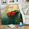 Ladybug throw blanket draped over a sofa with leafy garden artwork