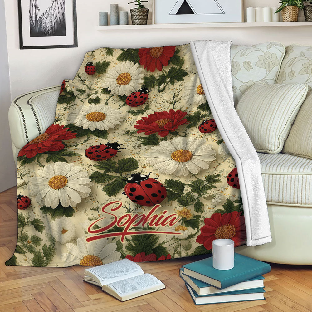 Ladybug floral throw blanket draped over a sofa with red blooms, daisies, and leafy greenery