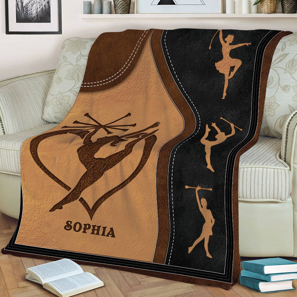 Close view of baton twirling blanket artwork with performer silhouettes and warm brown and black tones