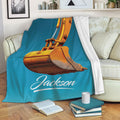Turquoise excavator throw blanket draped over a sofa with bold orange construction equipment artwork