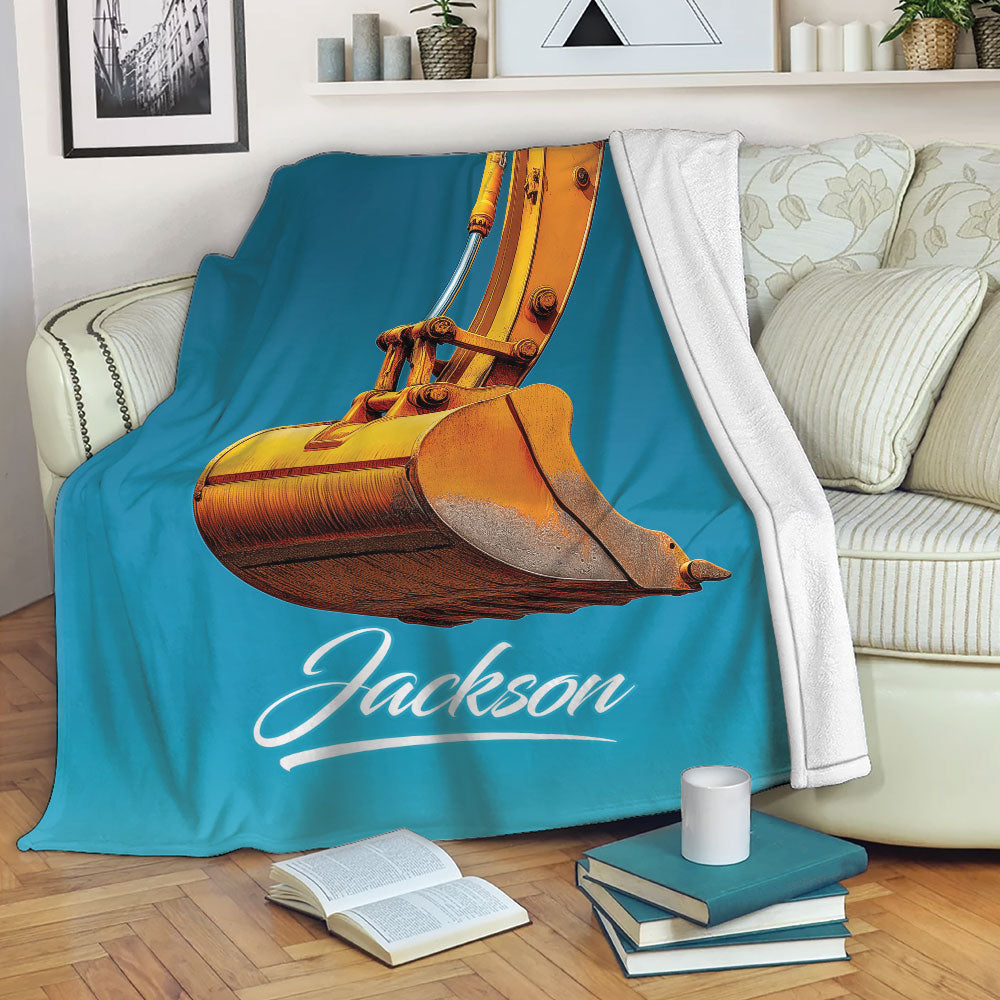Turquoise excavator throw blanket draped over a sofa with bold orange construction equipment artwork