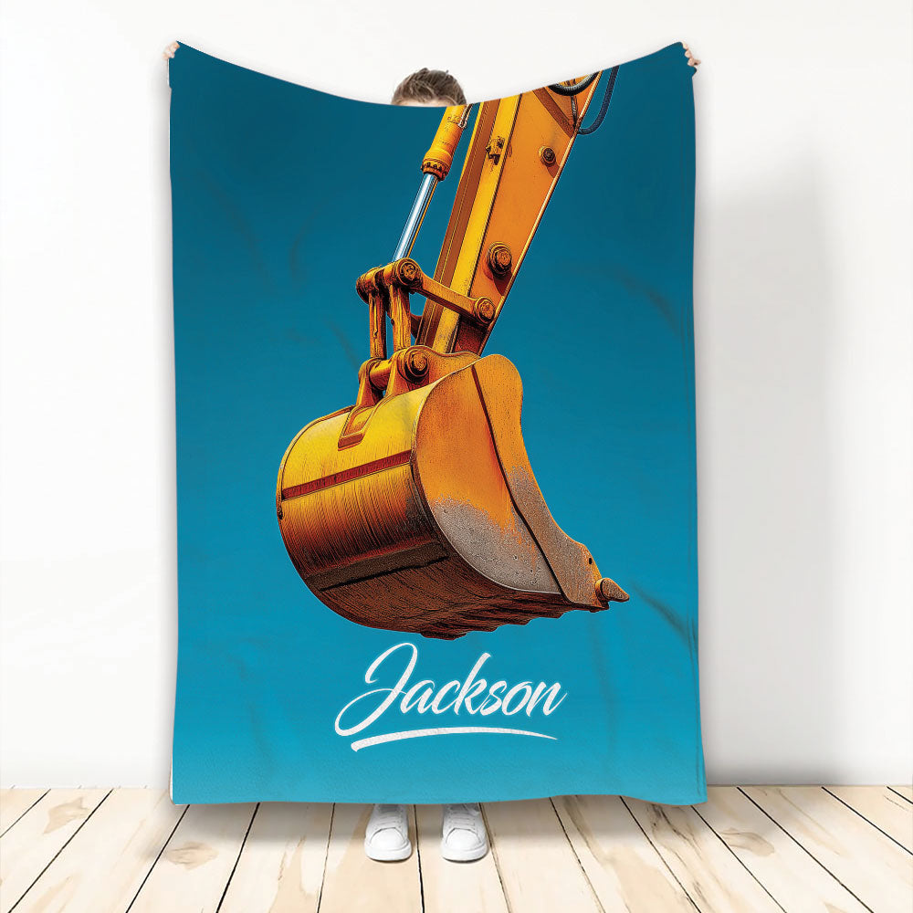 Orange excavator bucket artwork on a turquoise blanket shown hanging in a bright room