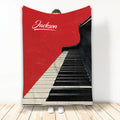 Red and black piano keyboard blanket displayed against a wall with a bold music-themed design