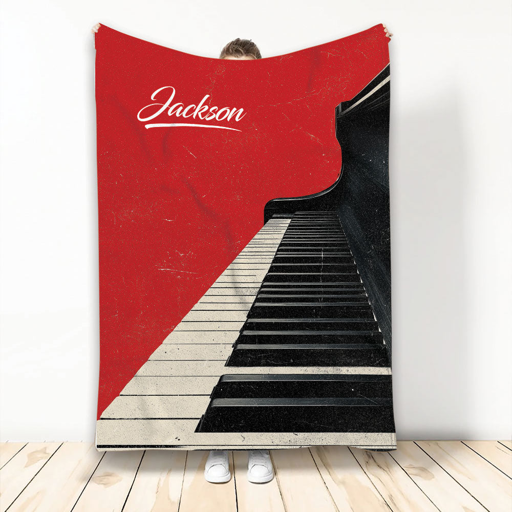 Red and black piano keyboard blanket displayed against a wall with a bold music-themed design